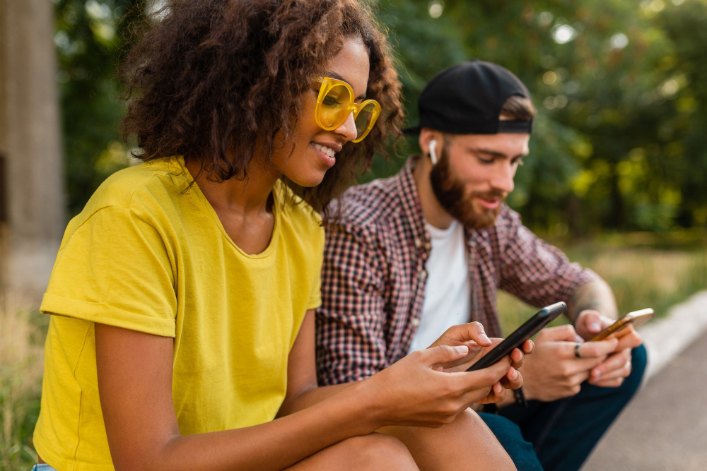 Ragazza con maglietta gialla e ragazzo con smartphone all'aperto